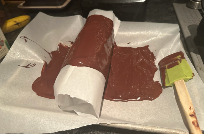 Melted chocolate spread over a roll of parchment.